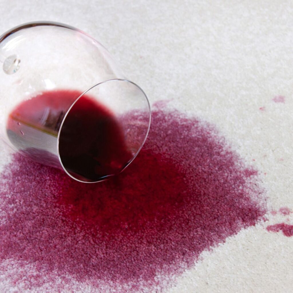 photo of a glass of red wine spilled on white carpet