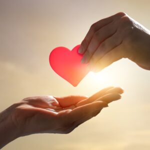 hand giving heart to another hand