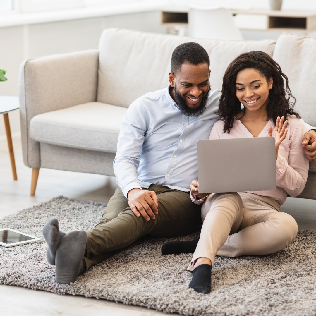 couple sitting on floor looking at laptop